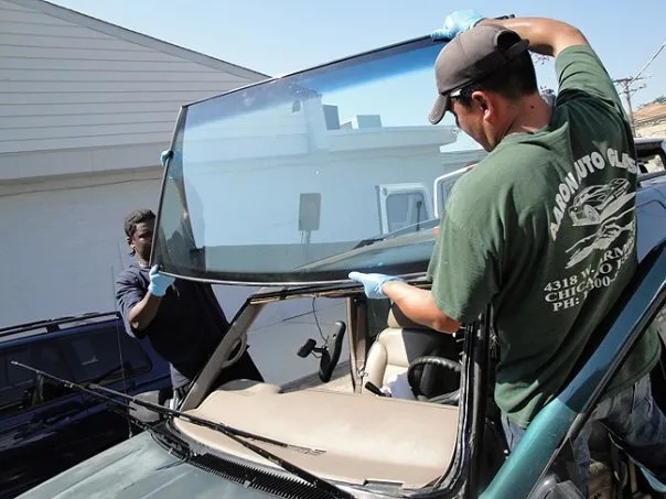 men installing a front windshield on a car