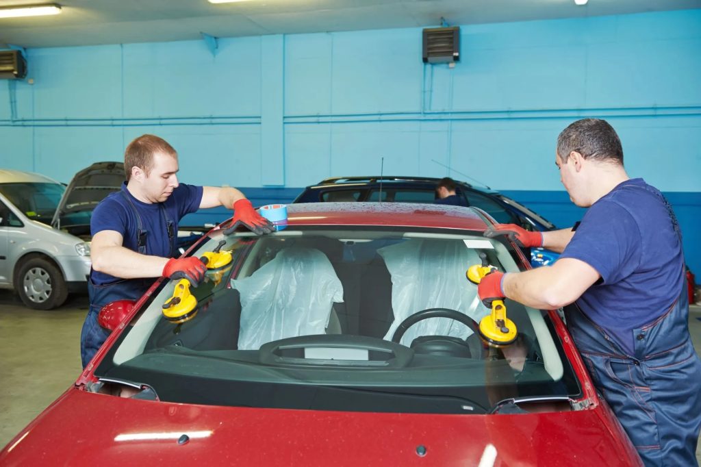 two people replacing windshield on car